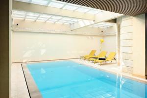 an indoor swimming pool with yellow chairs and a house at Maison Heym Bordeaux in Bordeaux