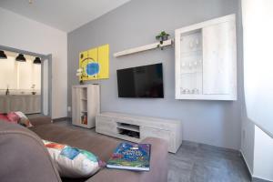 uma sala de estar com um sofá e uma televisão na parede em Casa Vacanze Family House posizione centralissima em Civitavecchia