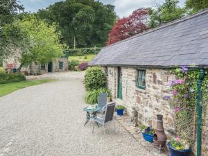 a stone cottage with a table and chairs in front of it at Rhyd y Brown Cottage Llys Y Fran in Pen-ffordd