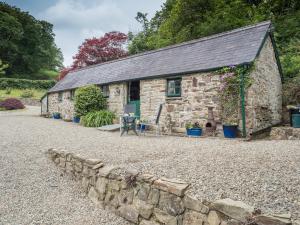 an old stone cottage with a stone wall at Rhyd y Brown Cottage Llys Y Fran in Pen-ffordd