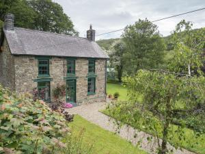 an old stone house with green windows and a garden at Rhyd y Brown Farmhouse Llys Y Fran in Pen-ffordd