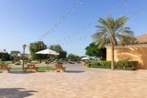 a patio with benches and an umbrella and a palm tree at Frank Porter - Canal Residence in Dubai