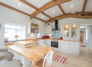 a kitchen with white cabinets and a wooden table at White Fields Cottage Carmarthen in Carmarthen