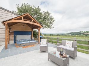 a patio with a grill and chairs and a table at White Fields Cottage Carmarthen in Carmarthen