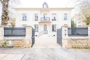 Uma casa branca com um portão à frente. em Villa Marie em Dijon