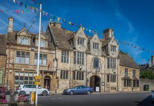 an old stone building with cars parked in front of it at The Talbot Hotel, Oundle , Near Peterborough in Oundle