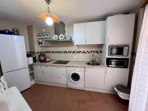 a kitchen with white cabinets and a washing machine at APARTAMENTOS TURíSTICOS MONTASOL 1 in Montánchez