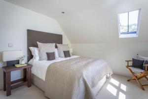 una camera da letto bianca con un letto grande e una sedia di Cable Cottage a Salcombe