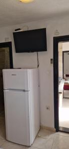 a white refrigerator in a room with a tv on the wall at Apartmani SLAVKO TUKA in Orebić