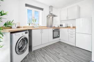 cocina con armarios blancos, lavadora y secadora en Stylish 2 Bedroom Apartment - Secure Parking - WIFI - Netflix - 27BC en Sleightholme