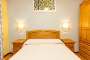 Un dormitorio pequeño con una cama y dos mesitas de noche. en Escuder Apartamentos Turísticos, en Ribadeo