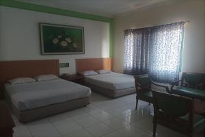 um quarto de hotel com duas camas e uma secretária e uma janela em Permata Hijau em Cirebon