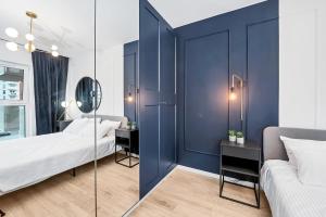 ウッチにあるLumina 2-room apartment with beautiful view Lodzの青い壁のベッドルーム1室、ベッド2台、鏡が備わります。