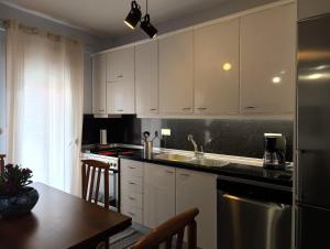 a kitchen with white cabinets and a sink and a table at NP apartment in Neoi Epivates