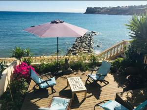 una terraza con sillas y sombrilla y el océano en PARADIS exceptionnel surplombant la MER- accès direct plage/ 8 Pers. en Carry-le-Rouet