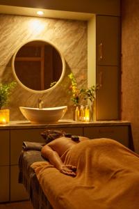 a woman laying on a bed in front of a sink at County Arms Birr in Birr