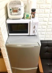 un forno a microonde seduto sopra un frigorifero di 4 minute walk to station. Direct to Shibuya and Shinjuku in 35minutes a Nishi-tsuruma