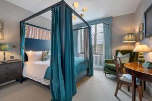 a bedroom with a canopy bed and a desk at Nevill Arms Inn in Medbourne