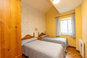 Un dormitorio con dos camas y una ventana. en Escuder Apartamentos Turísticos, en Ribadeo