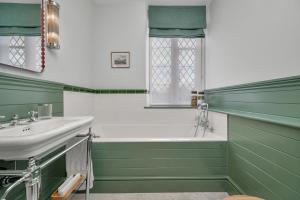 un bagno verde con vasca e lavandino di Nevill Arms Inn a Medbourne