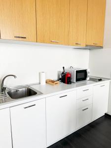 ティラナにあるMagnet Residence Condo 1 self checkinのシンクと電子レンジを備えた白いキッチン