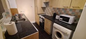 uma pequena cozinha com um lavatório e um micro-ondas em Super Comfy & Family Friendly Home em Leigh
