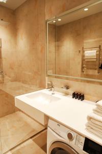 La salle de bains est pourvue d'un lavabo et d'un lave-linge. dans l'établissement Roze Center Apartments, à Liepāja