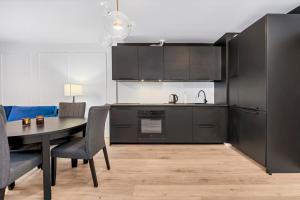 a kitchen with black cabinets and a table with chairs at Lumina bright apart Park Stefana Skrzywana in Łódź