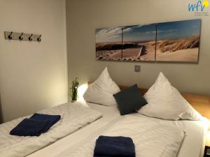 a bedroom with two beds with white sheets and blue pillows at Villa Vivaldi Ferienwohnung 2 in Wangerooge