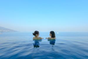 Dos mujeres sentadas en el agua en el océano en Atami Korakuen Hotel en Atami