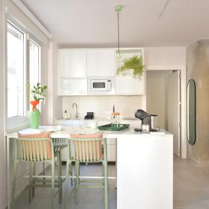cocina con armarios blancos, mesa y sillas en PATIO de SOMBRA · Urban Suites, en Granada