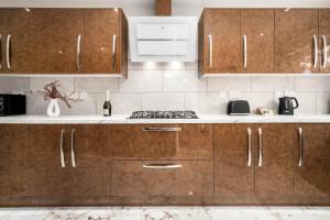 uma cozinha com armários de madeira e um forno com placa de fogão em Luxury 4 Bedroom House - Harborne - Top Rated - Parking - Garden - 6CO em Birmingham