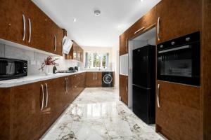 Luxury 4 Bedroom House - Harborne - Top Rated - Parking - Garden - 6CO في برمنغهام: مطبخ بدولاب خشبي وثلاجة سوداء