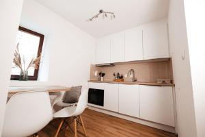 a kitchen with white cabinets and a table and chairs at Apartma Tuna in Izola