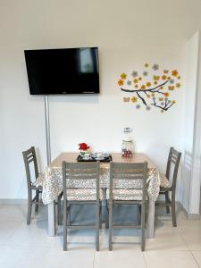 a dining room table with chairs and a tv on the wall at La Casetta tra Alghero e Stintino in Palmadula