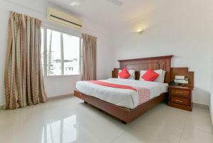 Schlafzimmer mit einem Bett mit roten Kissen und einem Fenster in der Unterkunft Centre Point in Kochi