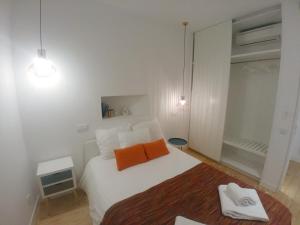a bedroom with a white bed with two orange pillows at Be Local - 2 bedrooms in front of the Fado Museum in Alfama in Lisbon