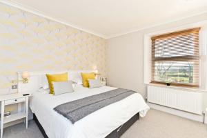 ein weißes Schlafzimmer mit einem Bett und einem Fenster in der Unterkunft Cliff House in Great Longstone