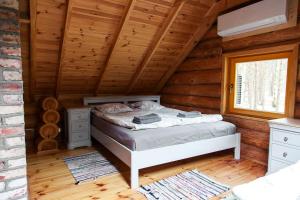 a bedroom with a bed in a log cabin at Roze Guest Houses Sklandas in Bernāti