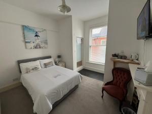 a bedroom with a white bed and a chair at Hotel 50 in Bournemouth