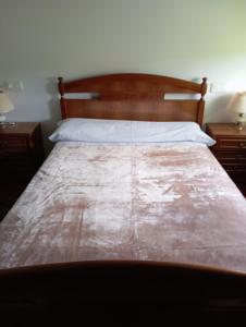 un letto con testiera in legno in una camera da letto di VT RURALRIA a Portomarin
