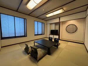 a living room with a table and chairs and windows at Chateraise Hotel Nagano in Nagano