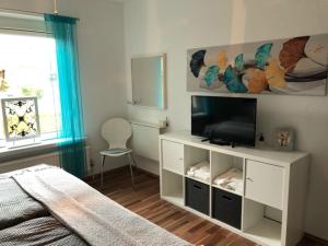 ein Schlafzimmer mit einem Bett und einem TV auf einem weißen Schrank in der Unterkunft Muuske in Emden