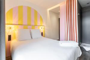 a bedroom with a large white bed with a colorful headboard at DEMAIN Hôtel in Nantes +43 photos