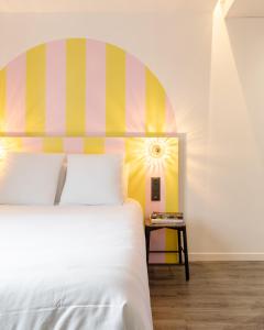 - une chambre avec un lit blanc et une tête de lit colorée dans l'établissement DEMAIN Hôtel & Conciergerie, à Nantes