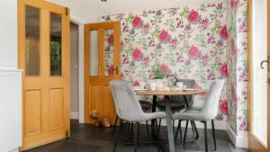 a dining room with a table with chairs and a floral wallpaper at Roslyn in Bakewell