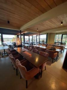 una sala da pranzo con tavoli, sedie e finestre di KARIBU - Olifant a Kasterlee