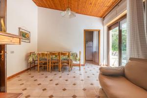 uma sala de estar com um sofá, uma mesa e cadeiras em Villa bifamiliare con giardino em Teulada