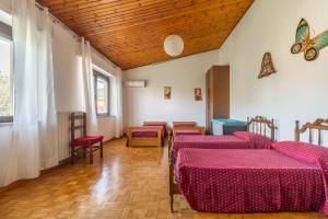 um quarto com 4 camas com lençóis e cadeiras cor-de-rosa em Villa bifamiliare con giardino em Teulada