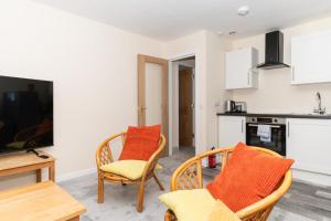 a living room with two chairs and a tv at Brilliantly Located 2BD Flat Heart of Edinburgh! in Edinburgh
